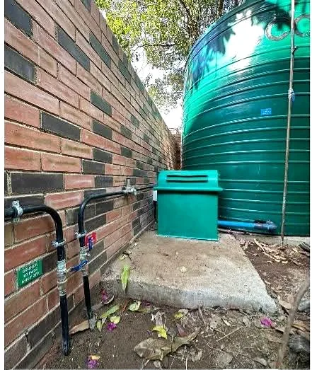 Water storage tank installed beside a garden wall