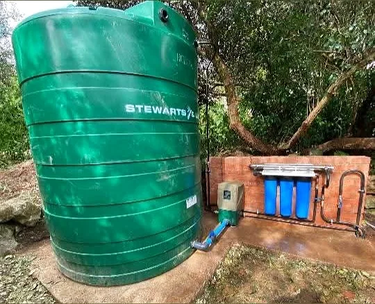 Water tank installed against a house with filter housings