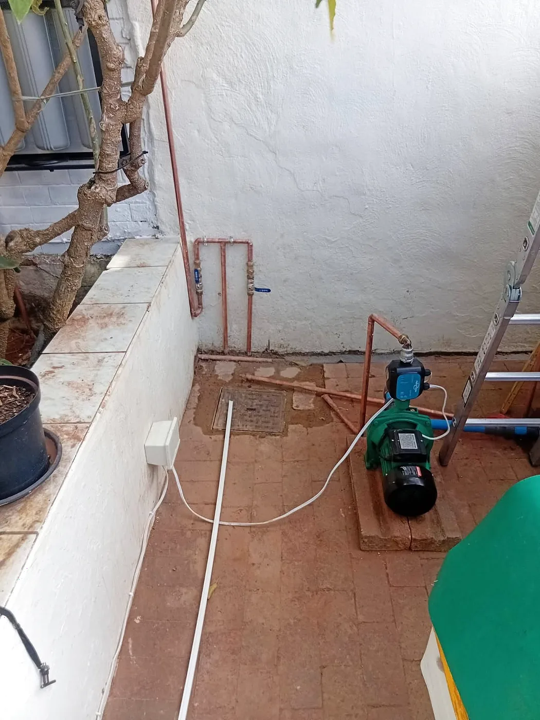 Water pump and pipework installed against a house wall