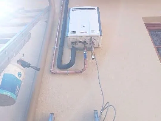 Gas water heater installed indoors with copper pipework
