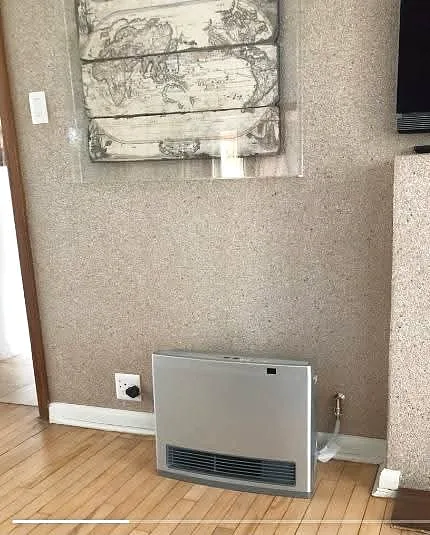 Gas water heater installed against a plastered wall